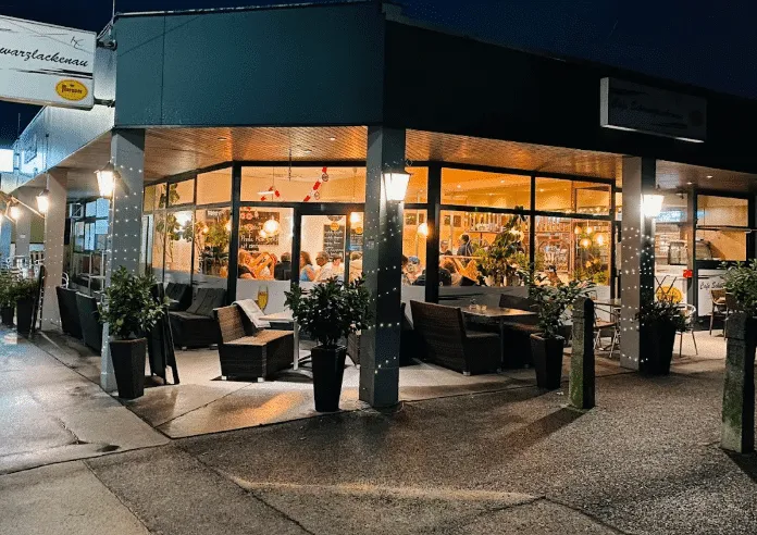 Die beleuchtete Terrasse der Pizzeria Schwarzlackenau in Floridsdorf am Abend